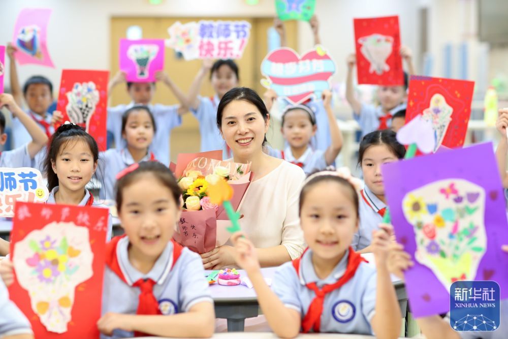 9月9日，在江苏省泰州市姜堰区实验小学教育集团北街北校区，学生手持手工制作的教师节贺卡和老师合影留念。新华社发（周社根摄）
