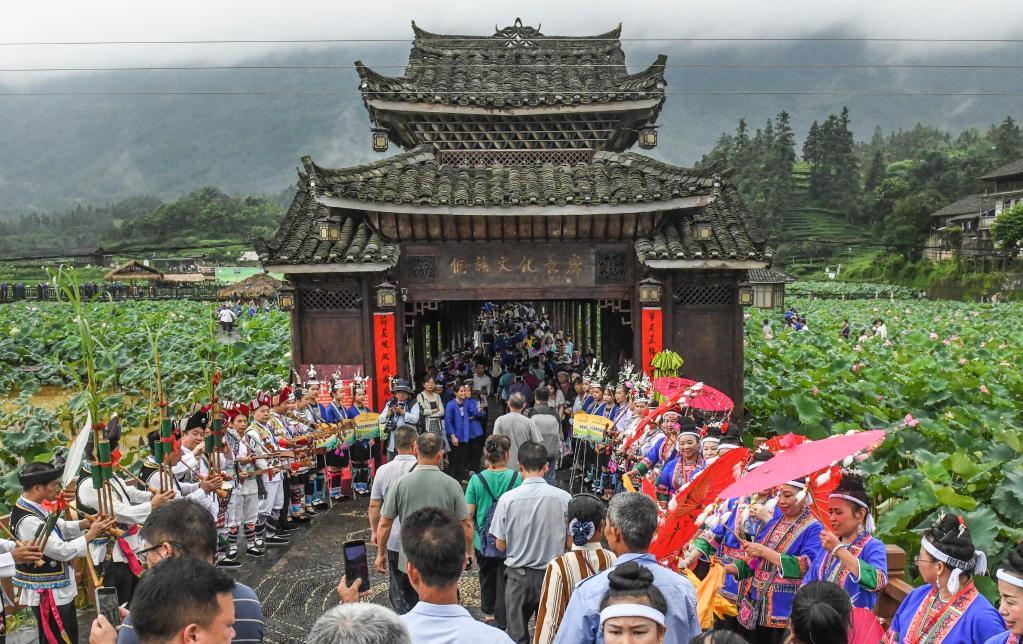 2025年6月28日，在广西三江侗族自治县良口乡和里村的侗族文化长廊前，村民吹奏芦笙欢迎游客。新华社记者 张爱林 摄