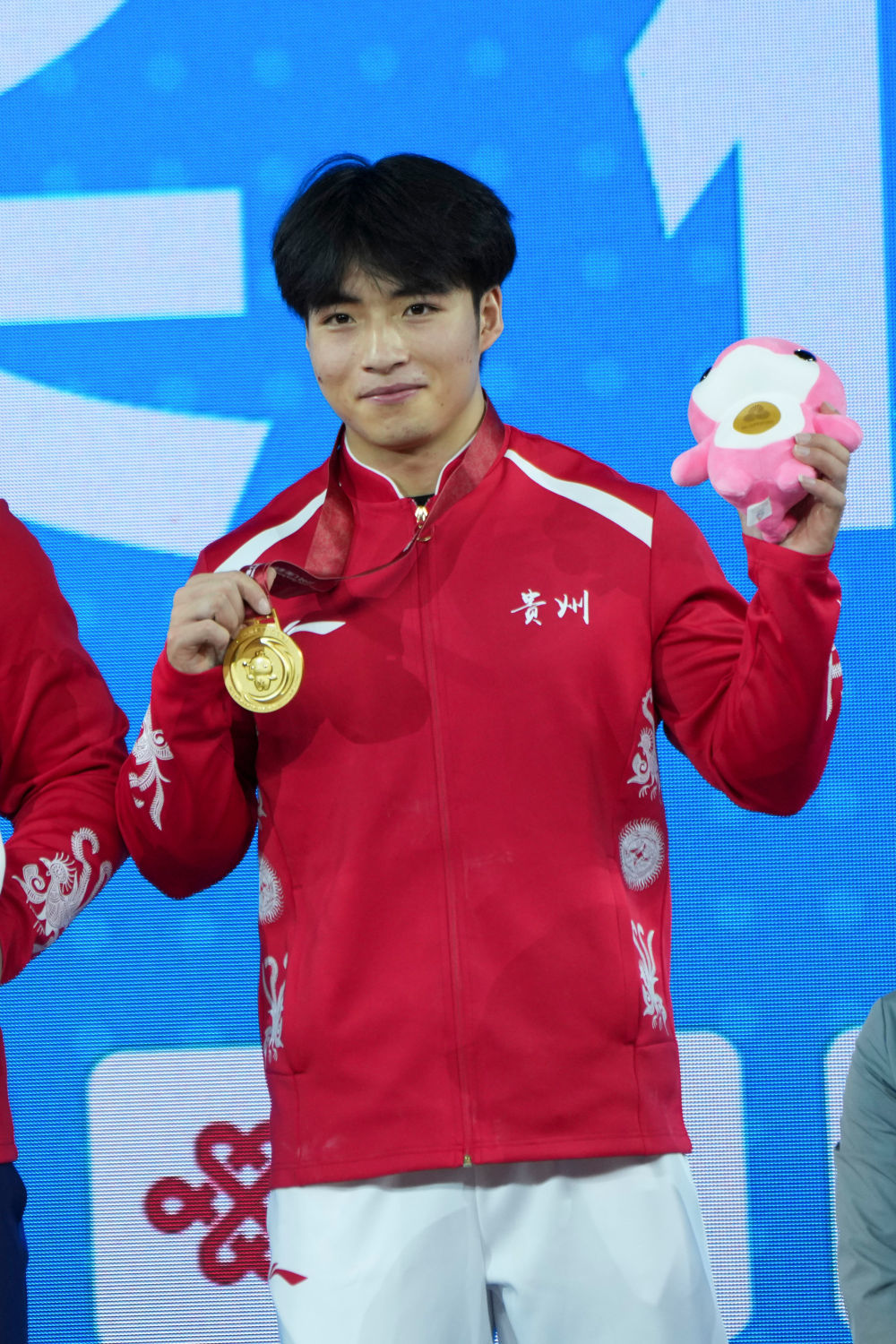 ↑11月18日,获得冠军的贵州队选手雷江清在颁奖仪式上展示金牌,他身上的贵州代表队服装上绣着传统纹饰。新华社记者 杨晨光 摄