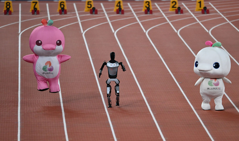 11月17日，在田径项目赛事开始前的暖场活动中，机器人和吉祥物喜洋洋、乐融融在广东奥体中心体育场赛跑。新华社记者 周牧 摄