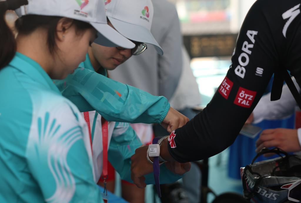 11月8日，在公路自行车男子个人赛决赛开赛前，志愿者为参赛选手佩戴通关手环。