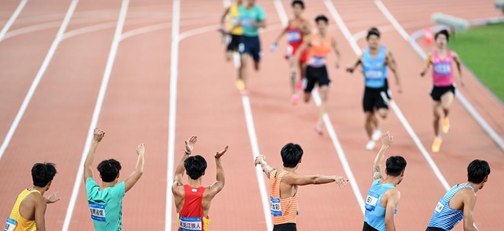 11月19日，在田径项目男子4X400米接力预赛中，参赛选手等待交接棒。