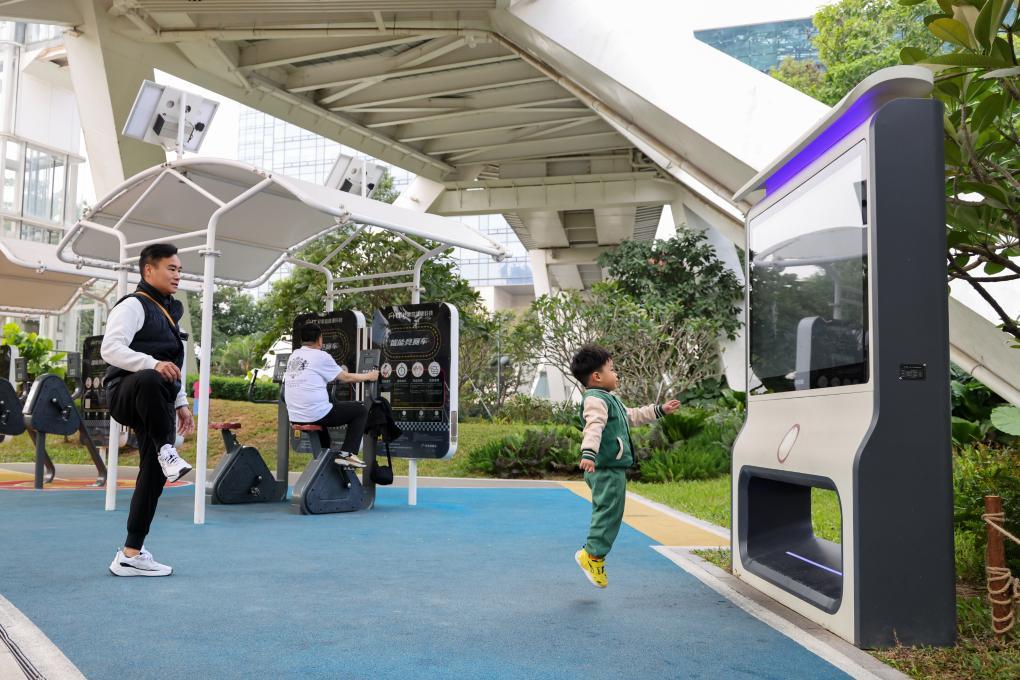 2024年12月27日，在深圳笔架山公园里，小朋友和家长一起使用智能互动屏锻炼身体。