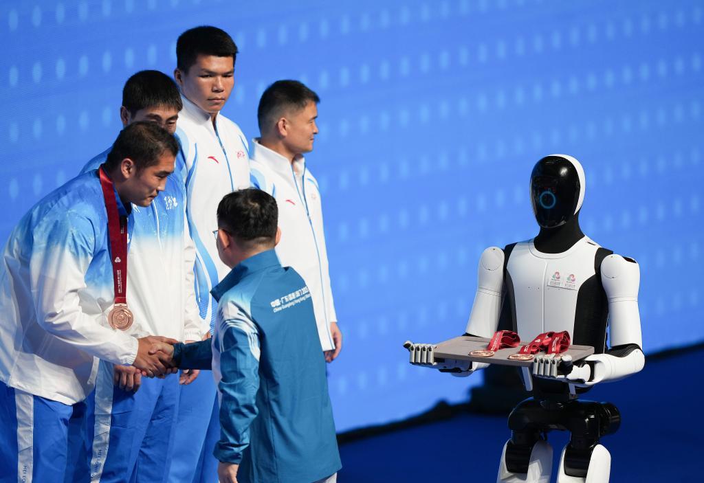 11月14日，人形机器人在拳击男子92公斤级颁奖仪式上为颁奖嘉宾递上奖牌。