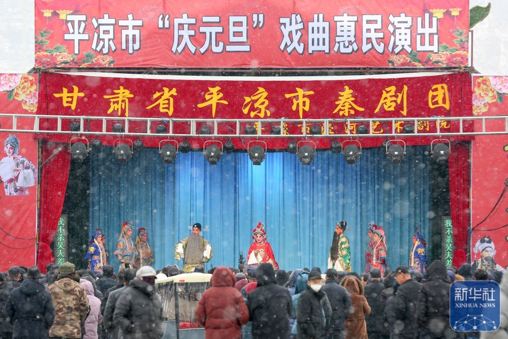 ↑ 1月2日，在甘肃省平凉市崆峒区，人们冒雪观看戏曲惠民演出。新华社发（吴希会摄）