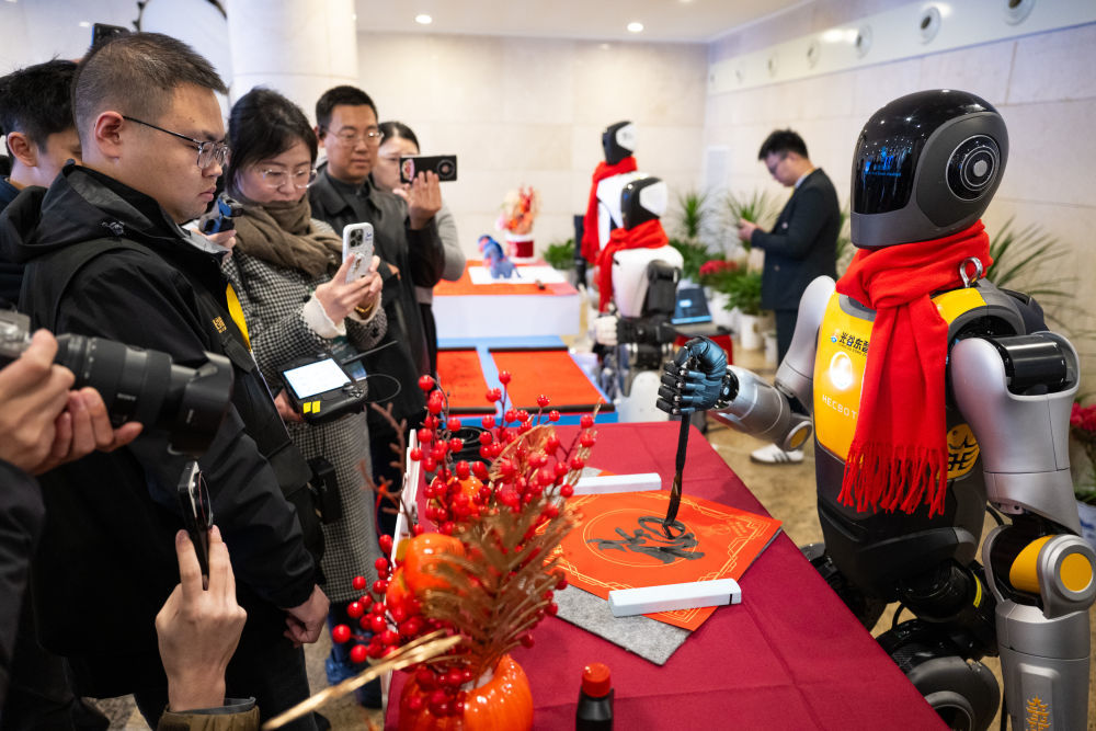 2026年2月24日，人形机器人在湖北省加快建成中部地区崛起的重要战略支点推进大会上亮相，现场进行书法表演。新华社记者 肖艺九 摄