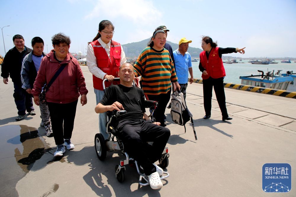 ↑ 5月16日，江苏省连云港市连云区连岛街道大路口社区志愿者带领社区残疾人参观海岛渔村。新华社发（王春摄）