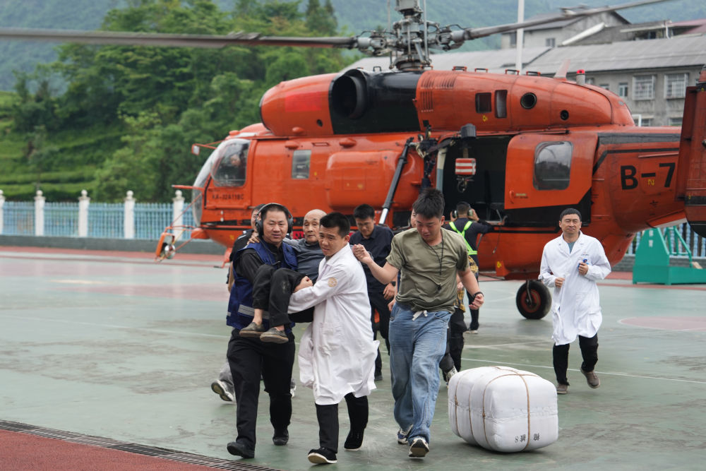 5月21日，人们在石门县南北镇中心学校帮助转移受灾群众。新华社记者 薛宇舸 摄