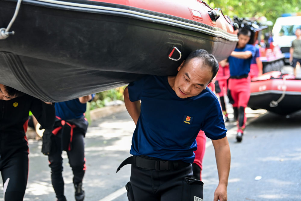 ↑ 7月10日，在广西贵港市救援一线，来自广西桂林市消防救援局的党员杨东升与战友一起将橡皮艇扛至预定水域。